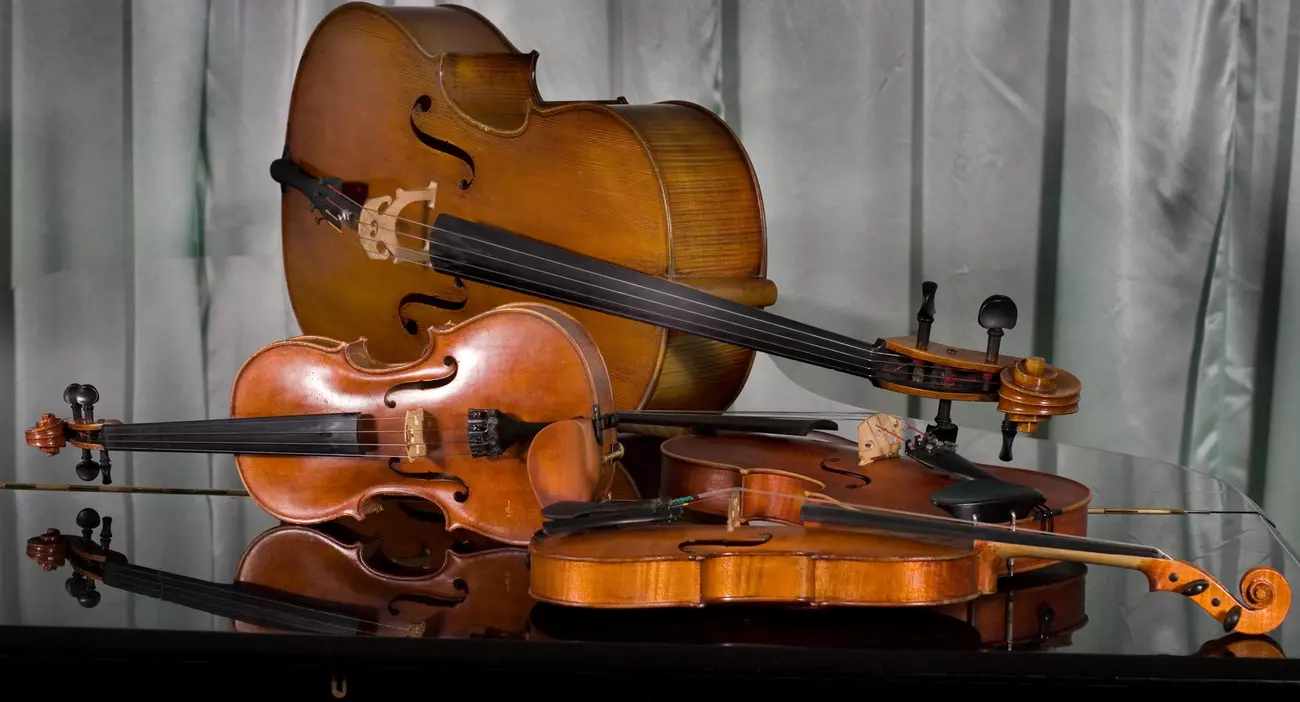 Quatre violons et violoncelle posés sur un piano