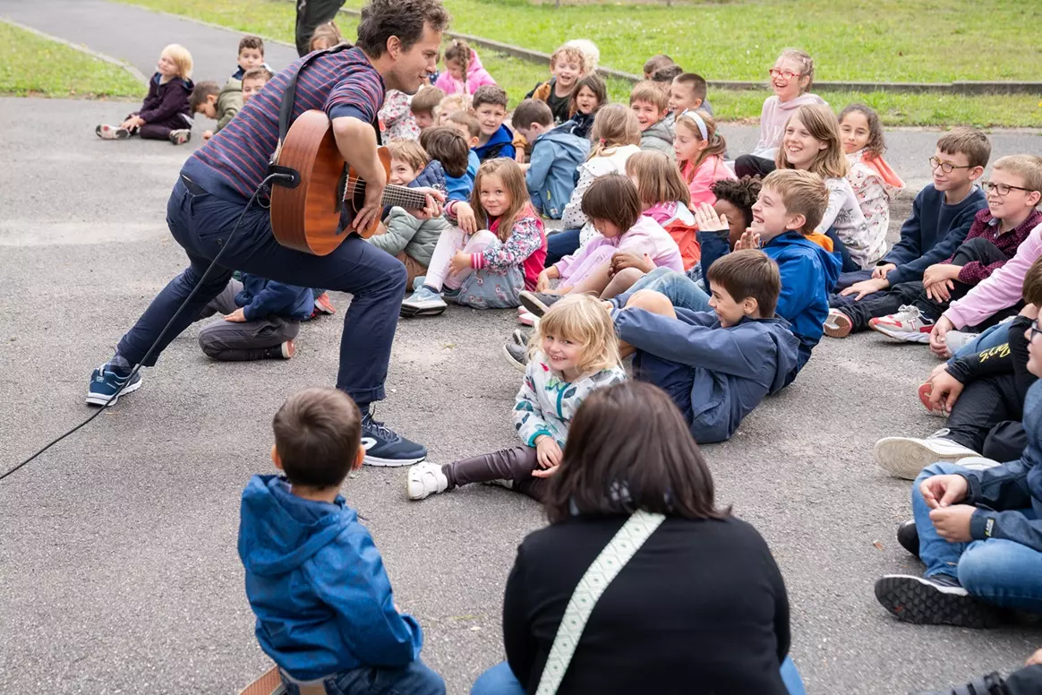 un guitariste joue devant des enfants