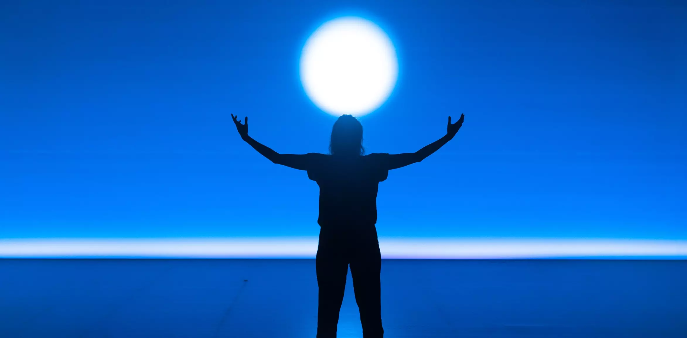 visuel du festival. un homme les bras levé vers le ciel avec une pleine lune en arrière plan