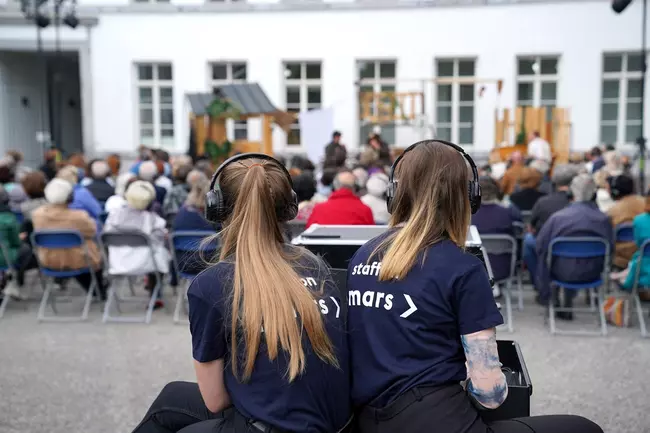 deux marsiennes derrière le public qui regarde un spectacle en extérieur