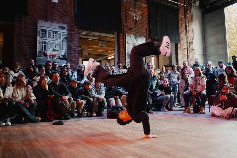 un danseur Hip Hop en plein mouvement au centre du public