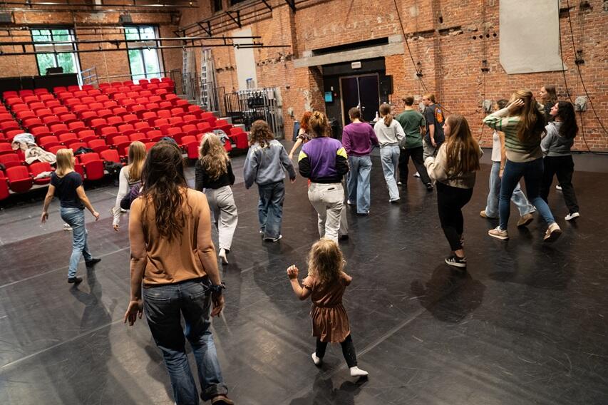 personnes de tous âges en train de suivre une initiation de danse avant un spectacle