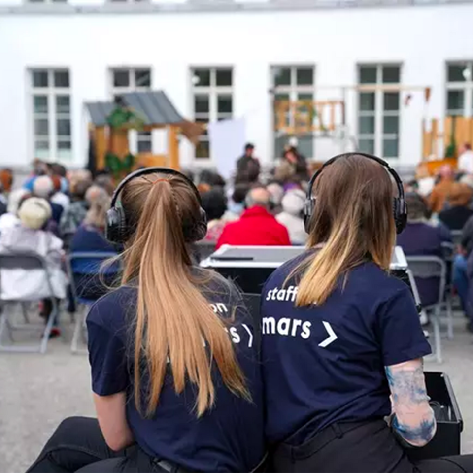 deux marsiennes derrière le public qui regarde un spectacle en extérieur